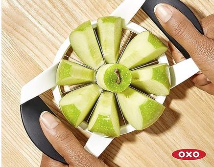 A pair of hands are using the apple slicer to cut a juicy green apple into 8 delicious pieces.