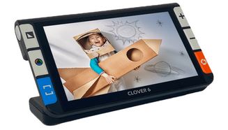 The Clover 6 is a thin black hand held digital video magnifier with a 5.5 inch touch screen. Also has tactile buttons on both sides. The left side has 3 buttons that control the contrast and reading guides. The right side has 3 buttons for magnification and picture taking.