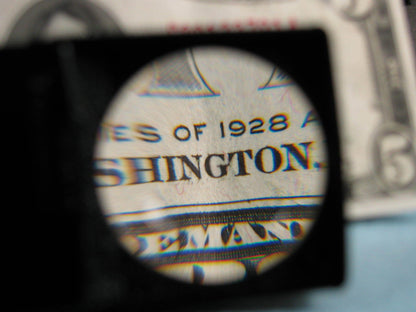 The magnifier is being used to look at a $5 bill