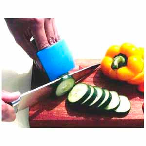 A Person chopping some cucumbers and peppers on a wood block. They are protecting their fingers with the guard